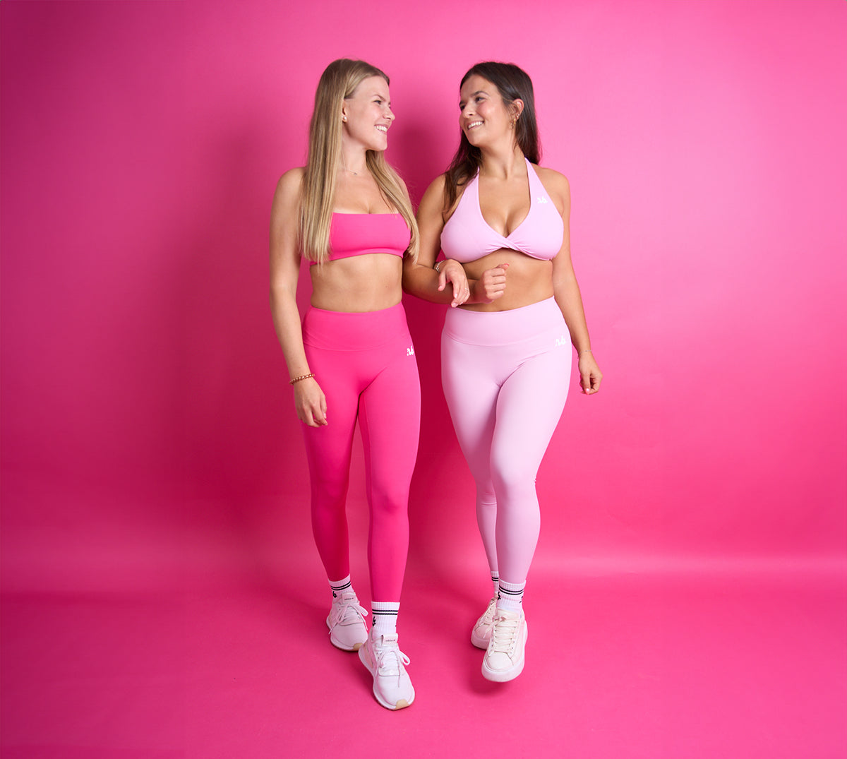 zwei Frauen in Sportkleidung in einem pinken Raum